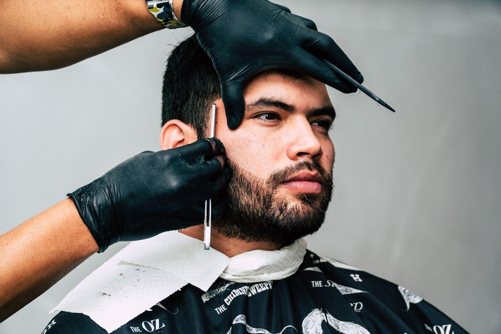 Barber lining up a client's beard with a straight razor
